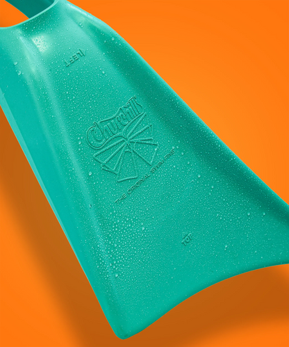 Teal Churchill swim fin with water droplets, embossed logo, against orange background