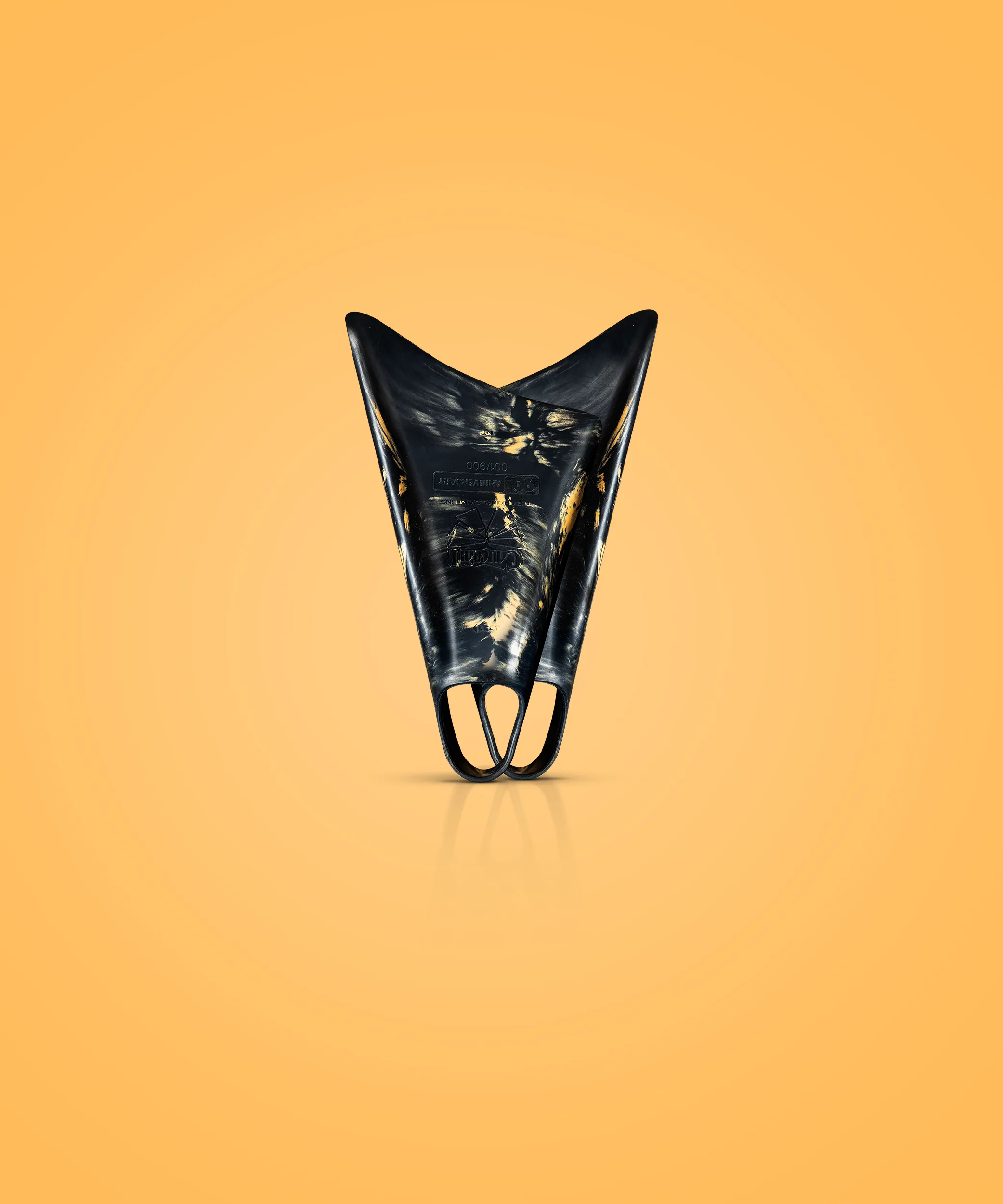 Black and gold swimfins with textured design, displayed against warm orange background for aquatic performance.