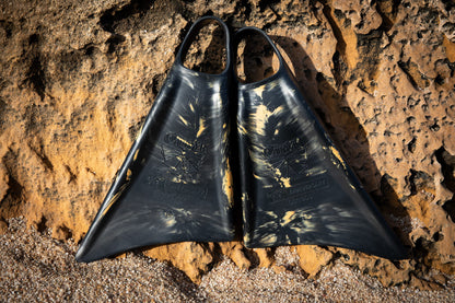 Black and gold Churchill swimfins on rocky beach, 90th anniversary edition, durable design for swimming